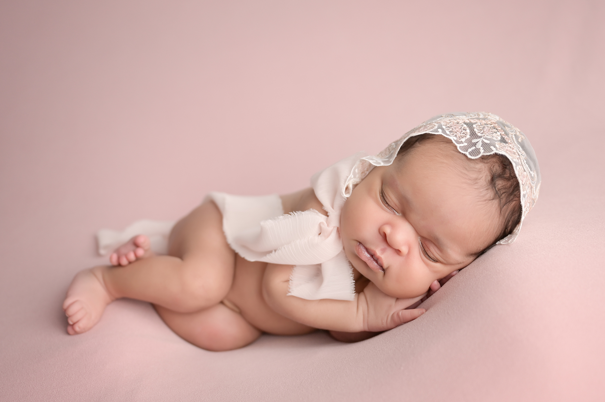 newborn session with Cherilyn Haines photography; newborn baby girl is photographed wearing a dainty lace and sequin bonnet