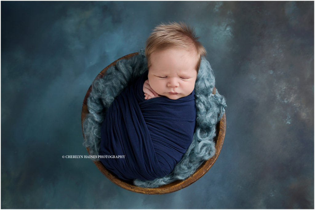 15 day old newborn baby boy photographed swaddled in navy on teal backdrop; cherilyn haines photography