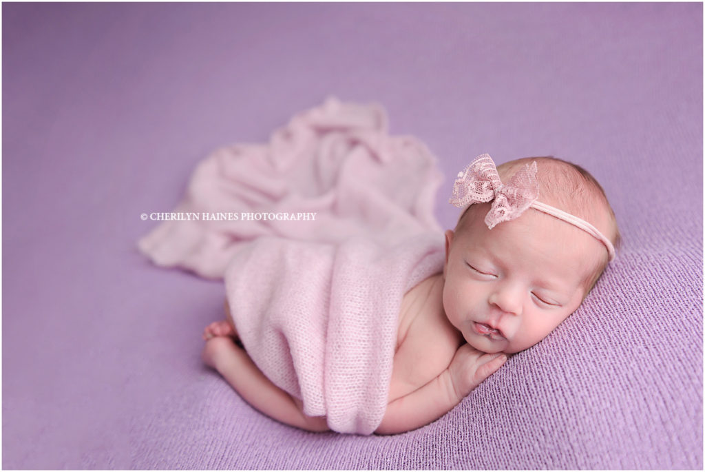 10 day old newborn baby girl photographed on purple blanket with pink lace bow; cherilyn haines photography in baton rouge, louisiana