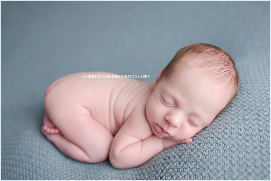 1 month old newborn baby boy photographed in tushie up pose laying on seafoam green blanket