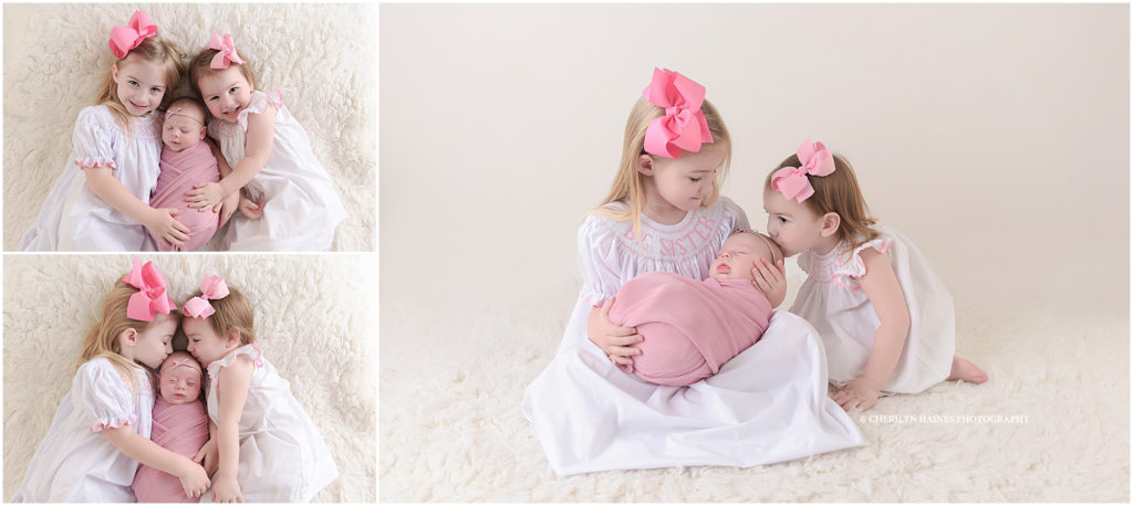 newborn baby girl photographed with two big sisters kissing her head in baton rouge, louisiana