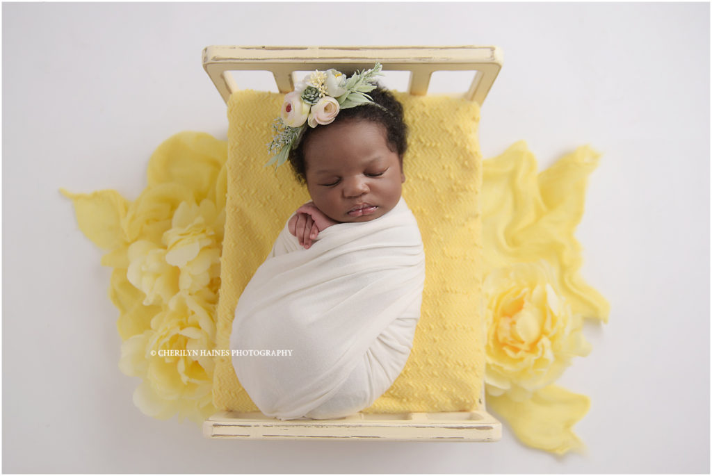 1 month old baby girl photographed sleeping on tiny wooden bed with yellow blanket; photographed in louisiana by cherilyn haines photography