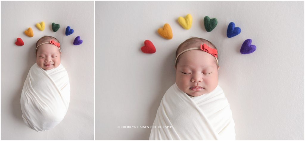 rainbow baby newborn portraits; newborn smiling with rainbow colored hearts