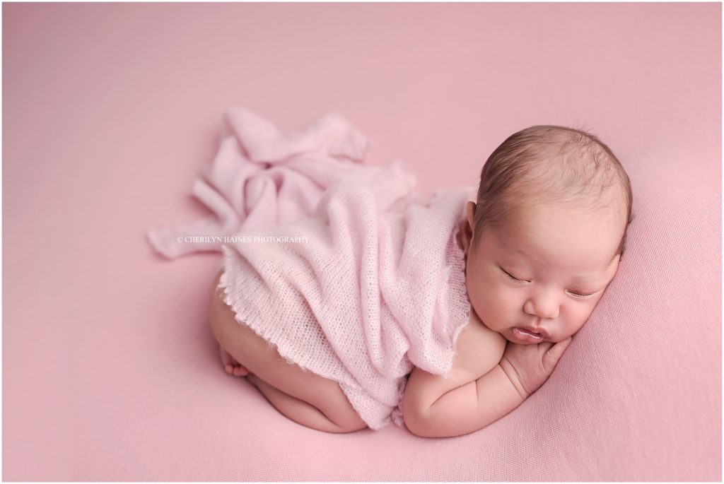 newborn baby photographed on light pink blanket; posed by cherilyn haines