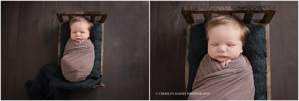 newborn baby boy photographed laying in brown wooden baby bed
