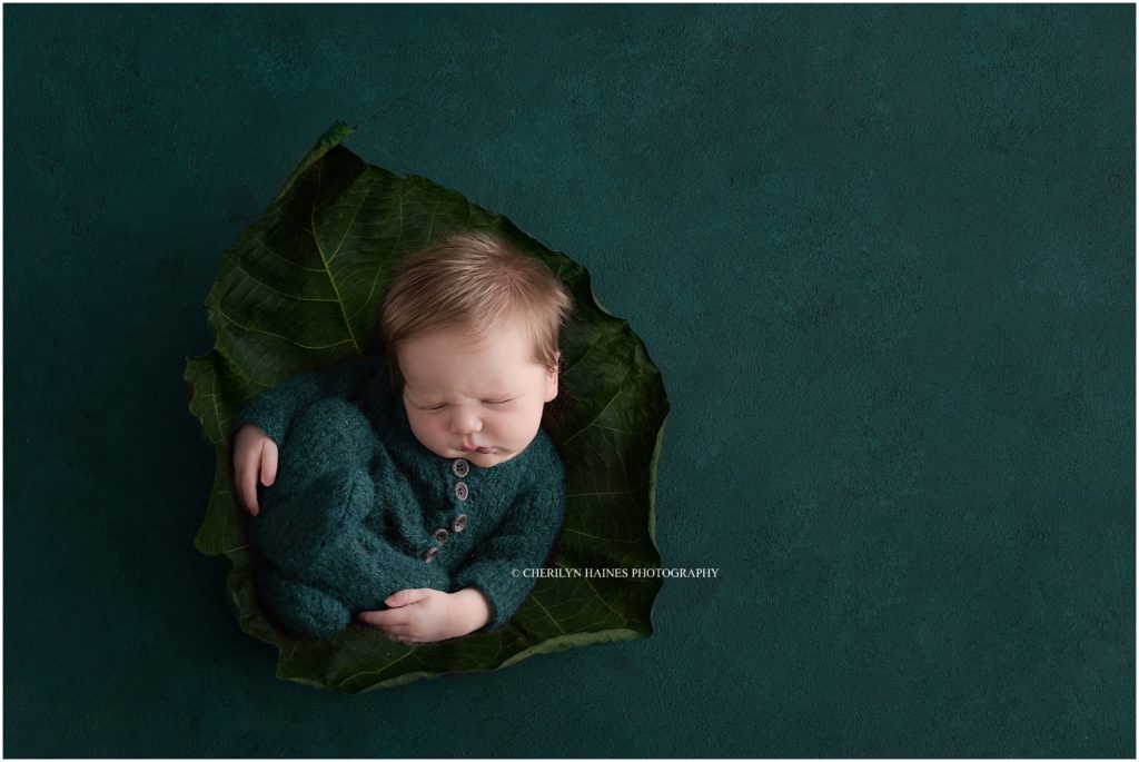 newborn baby boy wearing teal footed pajamas