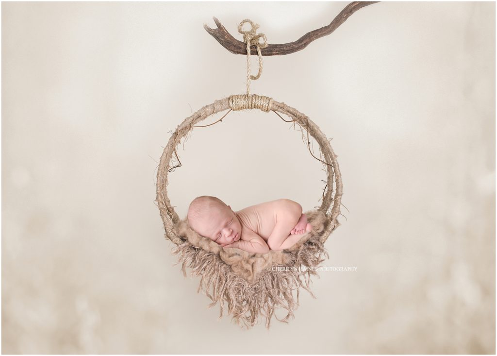 newborn baby boy photographed laying on hanging circular swing