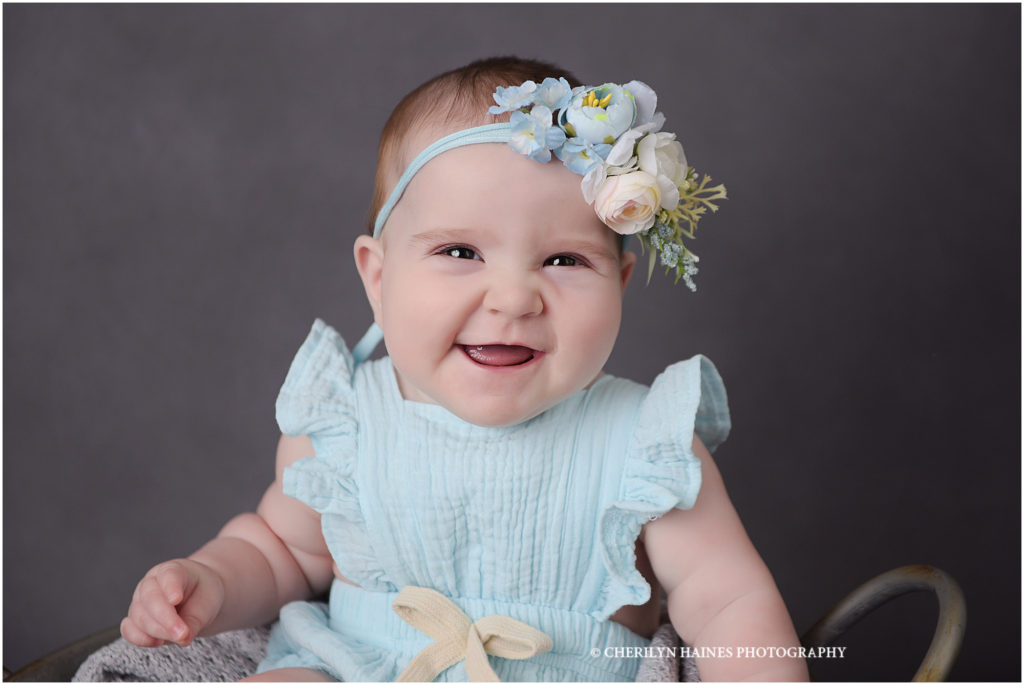 6 month old baby girl photographed by cherilyn haines while wearing a light blue romper with light plue and peach floral headband
