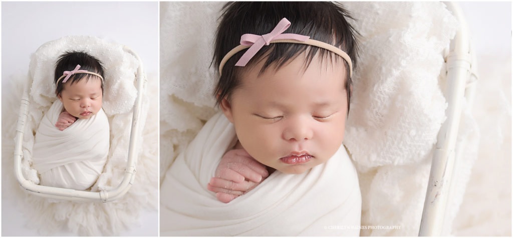 two week old newborn baby girl photographed swaddled in white photographed laying in white basket with white blanket