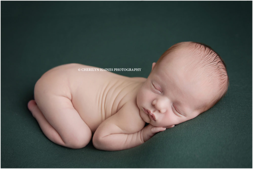 9 day old newborn baby boy photographed by cherilyn haines in baton rouge, louisiana; newborn posed on forest green colored blanket