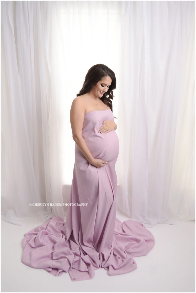 gorgeous pregnant mom photographed by cherilyn haines photography wearing light pink maternity gown in front of tall white windows