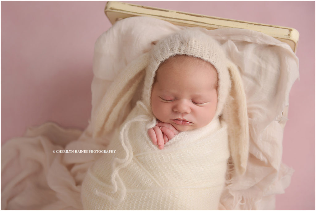 2 week old newborn baby girl photographed in knit bunny hat