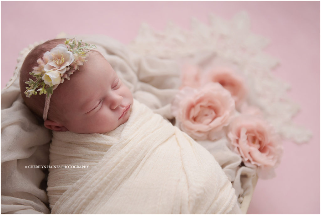 2 week old newborn baby girl photographed with pink flowers by cherilyn haines photography in new orleans, louisiana