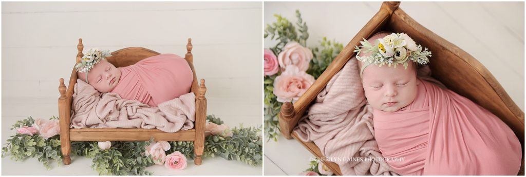 newborn baby girl photographed on tiny wooden day bed surrounded by pink flowers and greenery