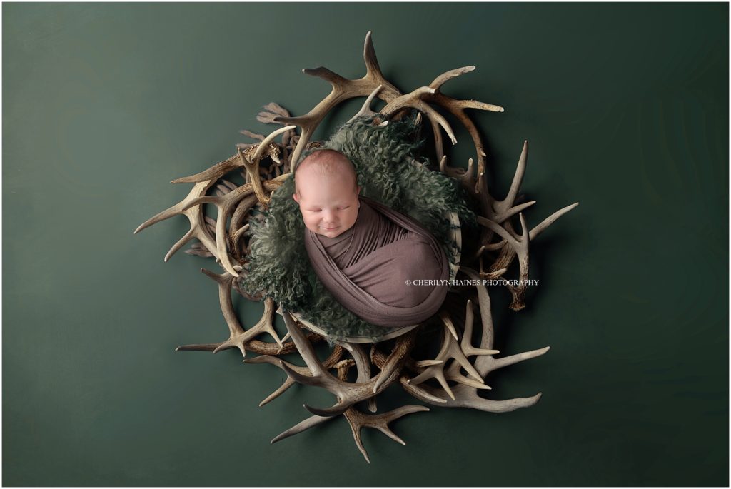 hunting themed newborn portraits with cherilyn haines photography; newborn baby boy laying in wreath of deer antlers