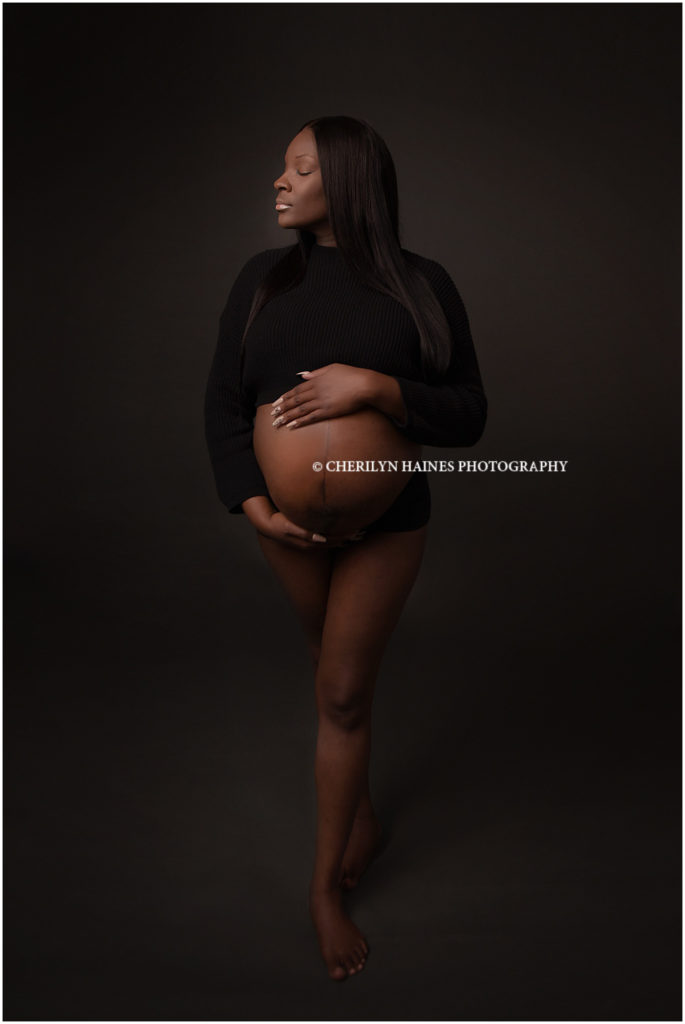 This expectant mom was photographed by Cherilyn Haines at her Baton Rouge, Louisiana studio. She chose a fine art style session and one of her chosen outfits was a black crop top showing off her round belly. Charmaine was just 12 days shy of delivering her baby when this picture was taken. Her long, straight hair and neutral makeup was the perfect style for this type of maternity portrait. 