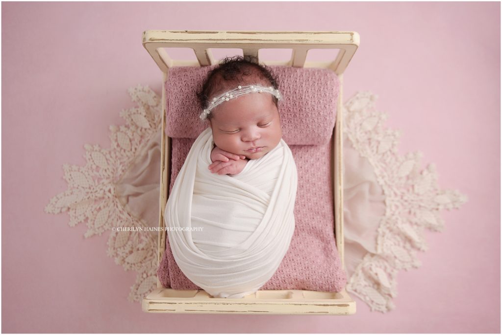 newborn portrait with baby laying on tiny wooden doll bed