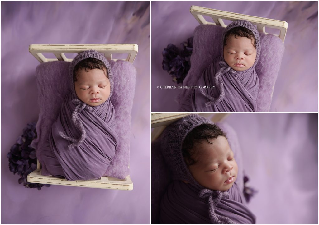 newborn baby girl photographed swaddled in tiny wooden bed, swaddled in purple swaddle with knit bonnet