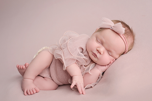 Newborn baby posed in a pink outfit during Baton Rouge studio session