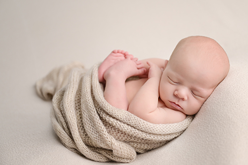 Sleeping newborn baby posed on soft blanket in Baton Rouge photography studio