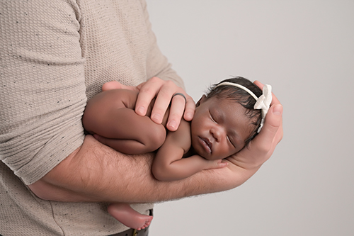 Sleeping newborn baby posed on dad's arms in Baton Rouge photography studio