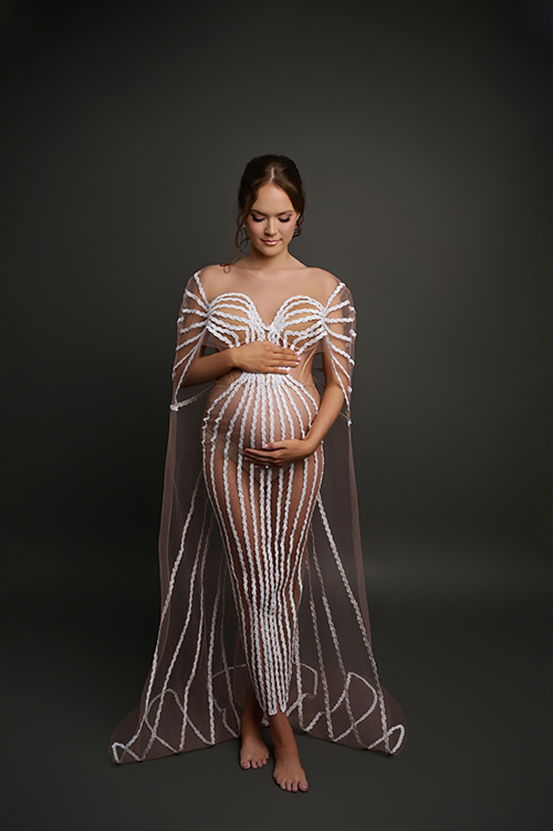 Elegant pregnant woman posing in a glamorous beaded maternity gown during a luxury maternity photo session in Baton Rouge.