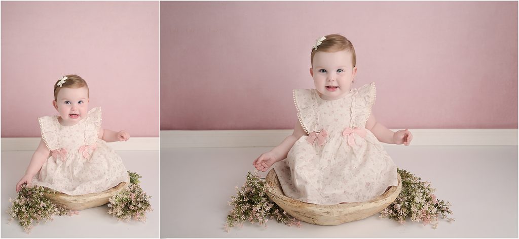 6 month old baby girl posing with flowers on a soft pink floral backdrop at a Baton Rouge photography studio