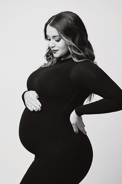 Black and white maternity portrait of an expectant mother wearing a fitted black gown during a luxury studio session in Baton Rouge.