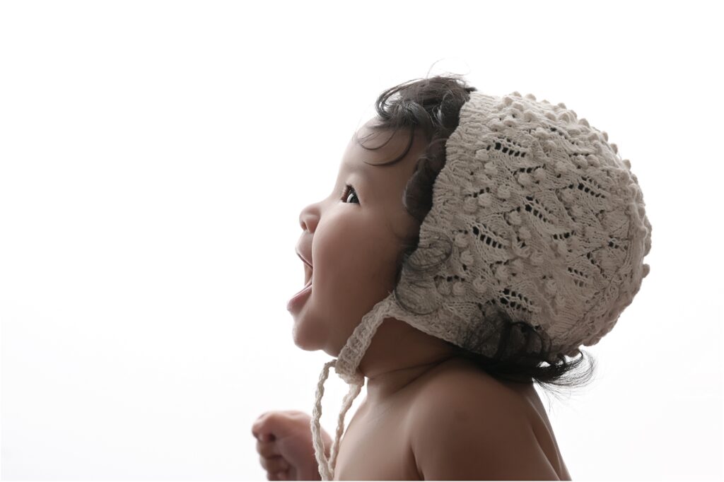Smiling 6-month-old baby girl looking up in a profile portrait