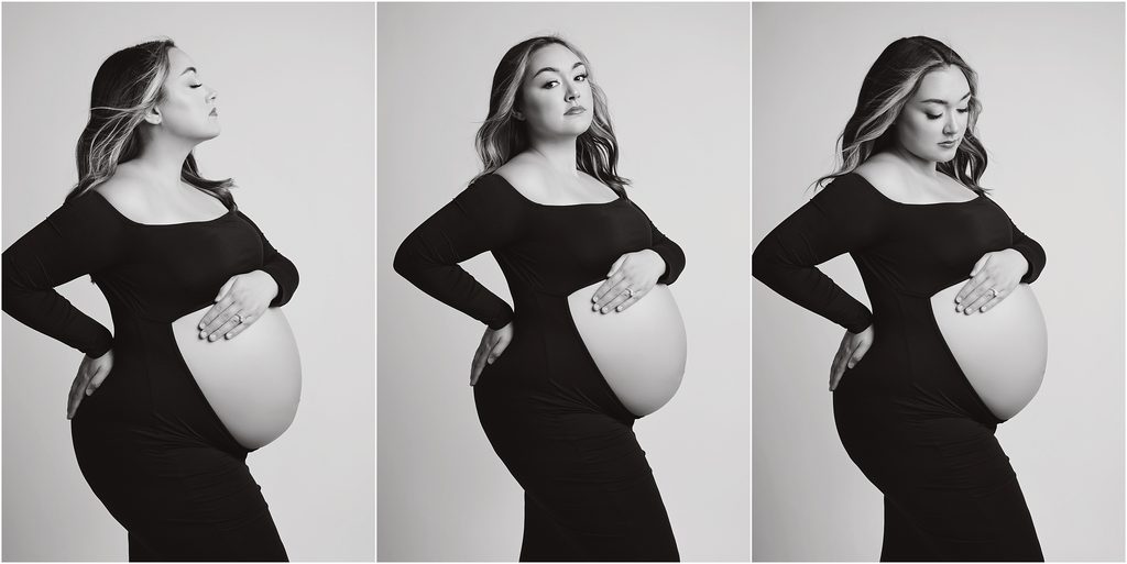 Black and white maternity portrait of pregnant mom in a formfitting black gown with her belly showing on a white studio backdrop
