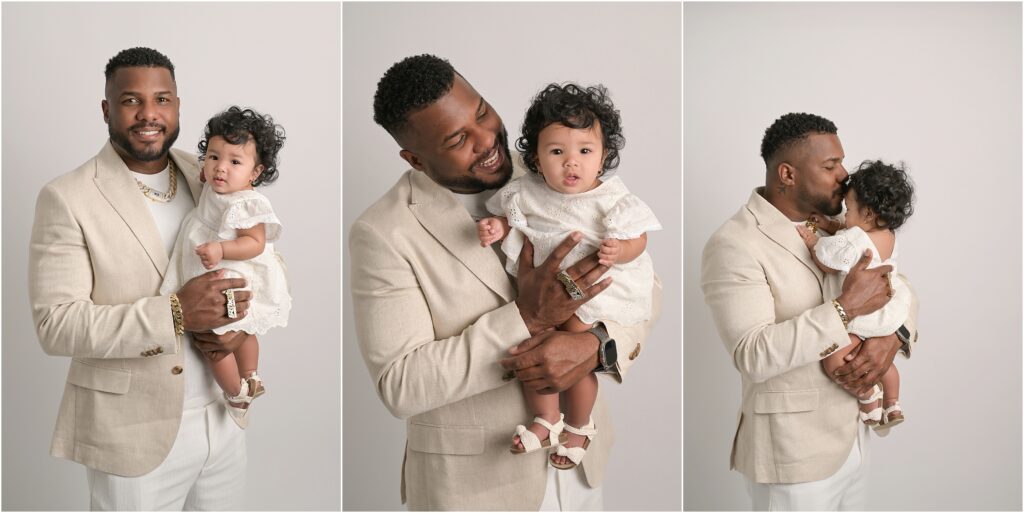 Daddy and 6-month-old baby girl posed together on a white backdrop