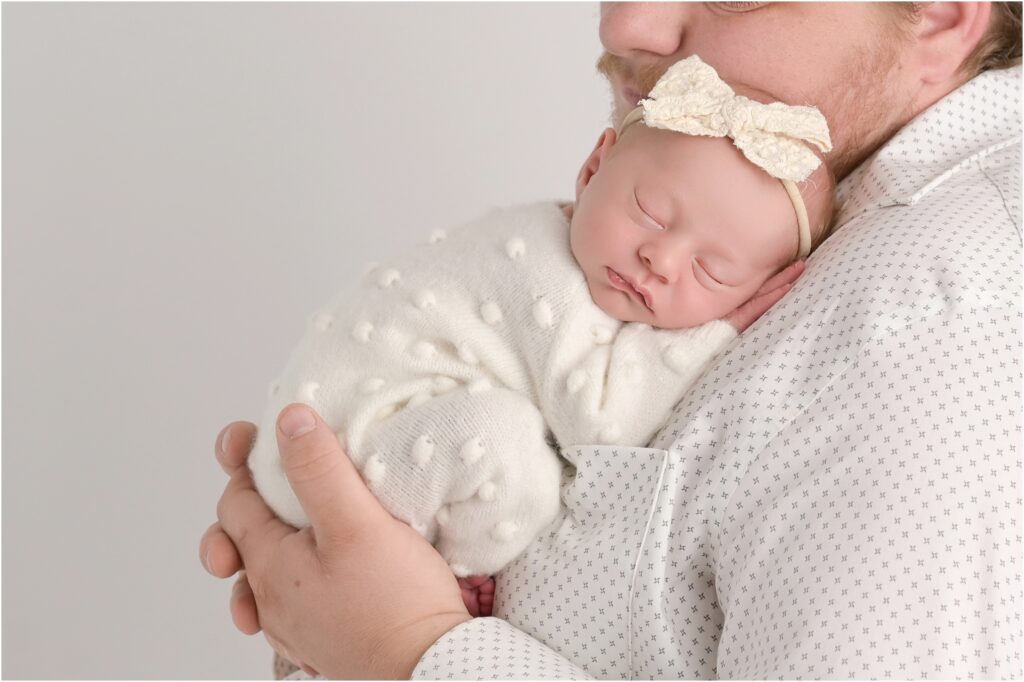 Tiny newborn baby girl resting in her father's hands