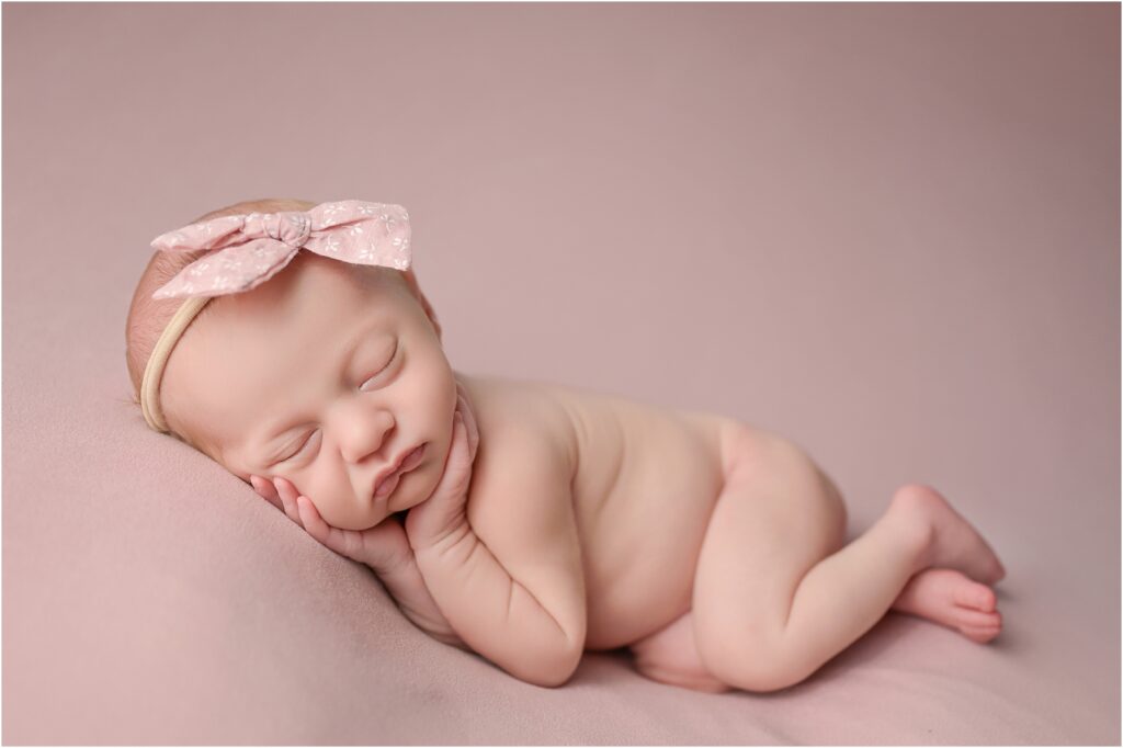 Sleeping newborn baby girl with her hands resting on her cheeks