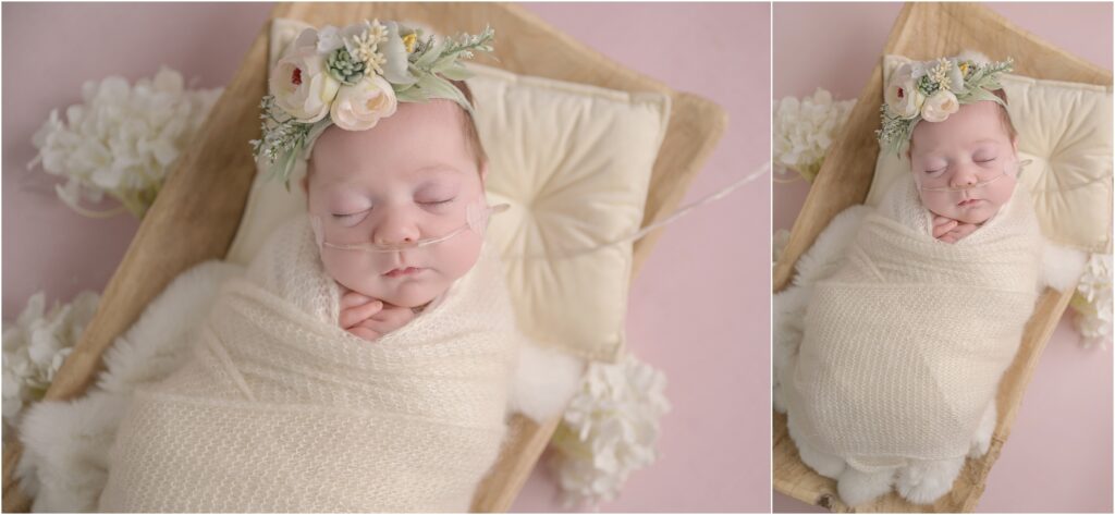 Baby girl in an ivory knit swaddle and floral headband surrounded by white and green flowers